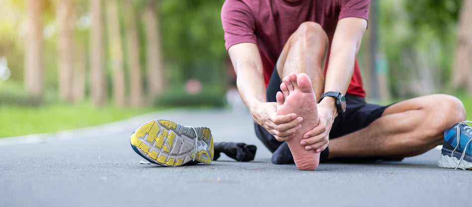 Plantar fasciitis blog post cover image man holding foot in pain when out on a run